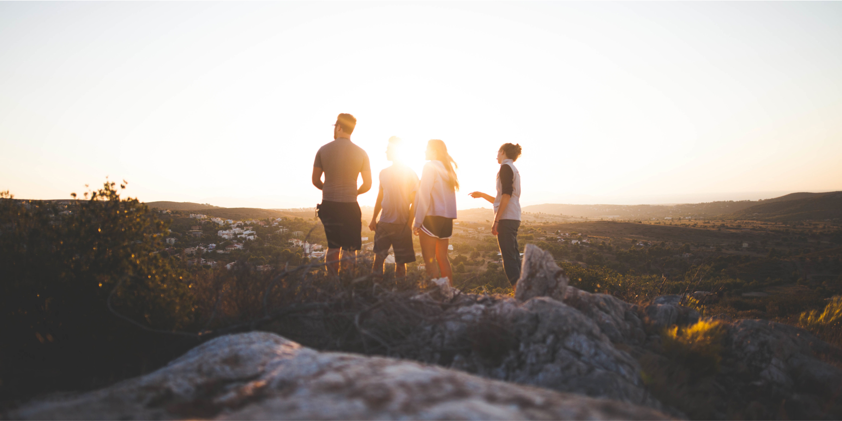 Group of people in a field at sunrise.