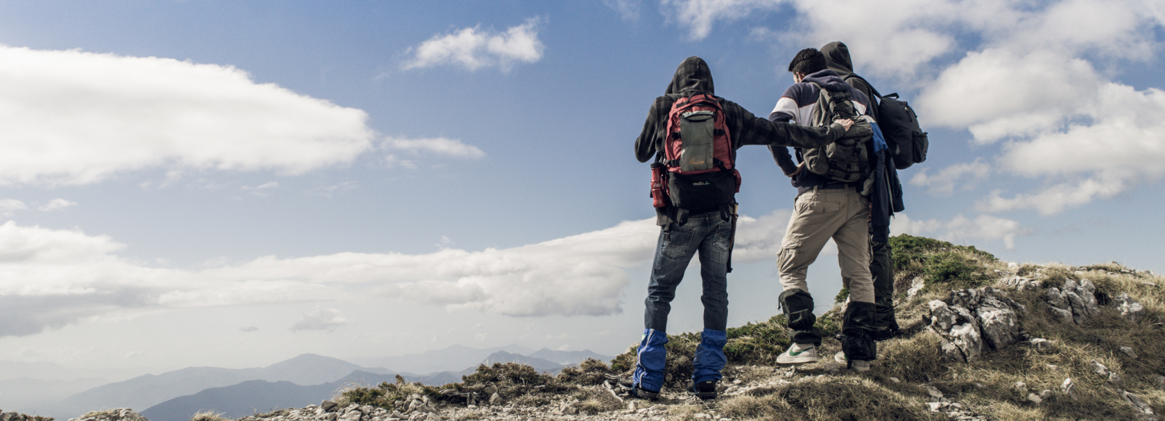 Three travelers standing on rocks with a view.