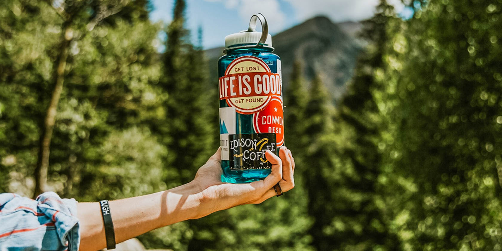 Person holding a reusable water bottle covered in stickers.