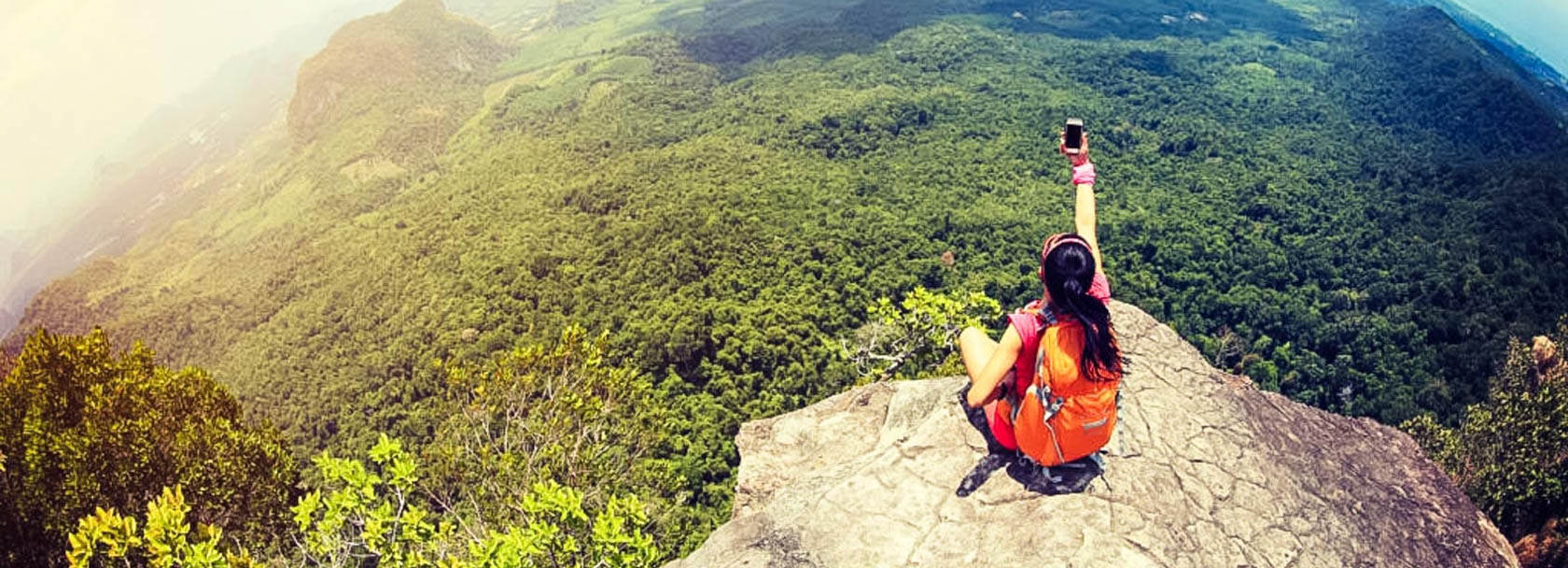 Solo traveler taking a selfie on top of a mountain.