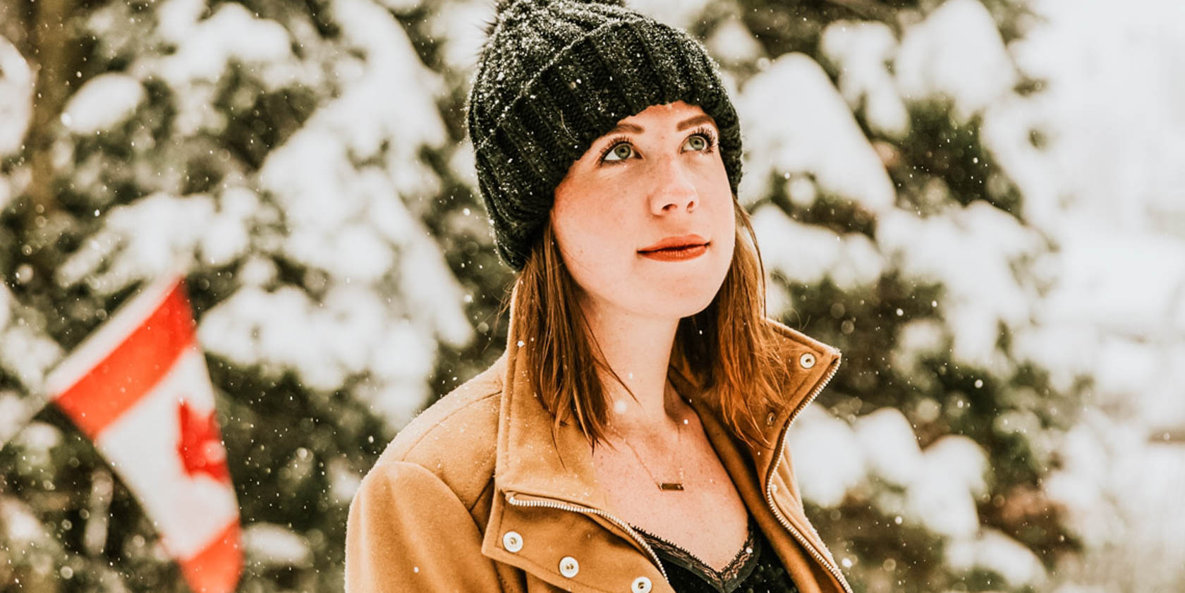 Solo traveler with a beanie in the snow and a small Canadian flag.